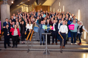 Many people on the stairs celebrating and cheering in Scottish Parliament.