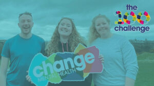 Three people standing with change mental health sign and the 100 challene logo in the corcer