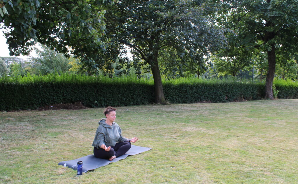 A women on the yoga mat practicing mindfulness through meditation in nature