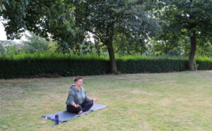 A women on the yoga mat practicing mindfulness through meditation in nature