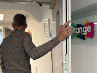 World Mental Health Day - access to services - man entering a room with Change Mental Health logo