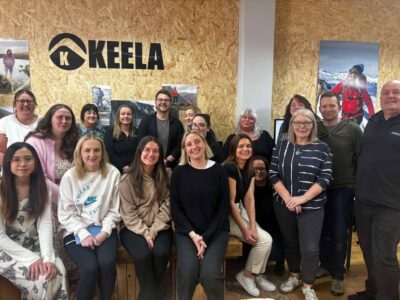 Change Mental Health training team with Keela Outdoors team during the delivery of the Building Resilience in the Workplace session - group of people standing in front of Keela Outdoors logo