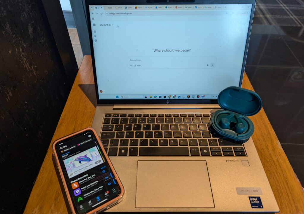 technology and mental health - laptop with opened chatgpt, airpods and a phone with app store