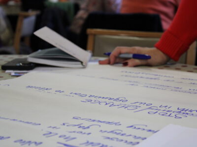 co-production in mental health - young people with lived experience - photo of of an A2 paper with list of things and a women with a sharpie in hand