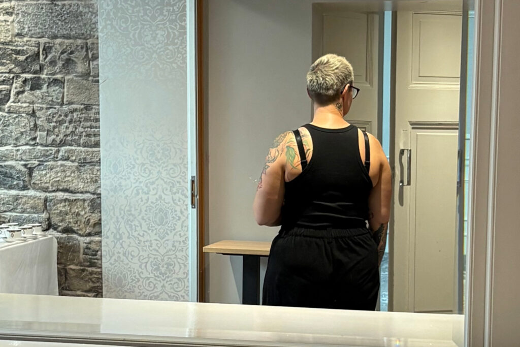 understanding stigma - womens reflection in the mirror looking towards the doors