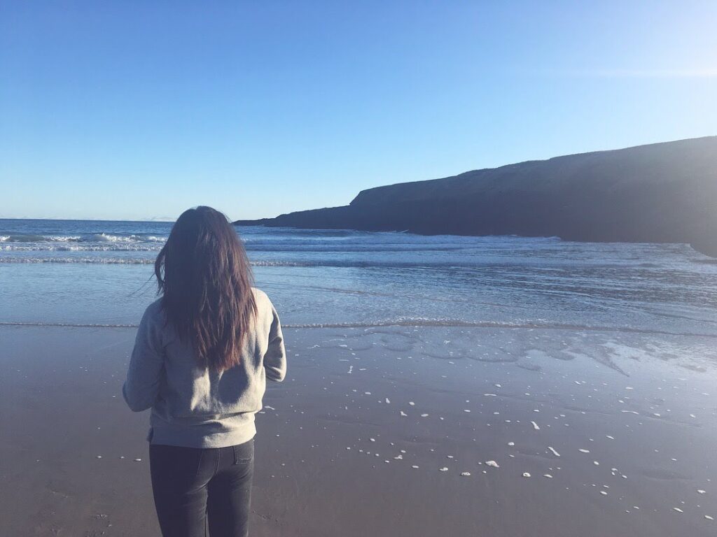 Sophie who benefited from DBI support when recovering from burnout - women standing at the beach looking at the sea