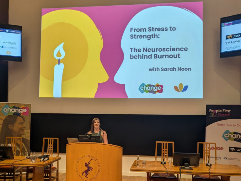 Women during the presentation with title saying: From stress to strength: The neuroscience behind burnout