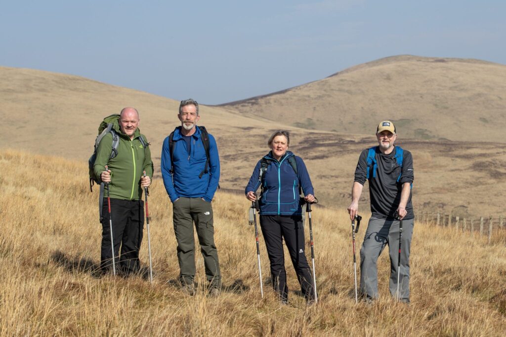 A picture of four people walking in the hills: Scott Dunsmore, David Fraser, Tina Fraser and Paul Henderson.