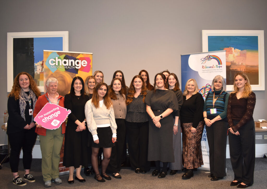 GM Charity Partner 2 resized - Change Mental Health A bunch of people in a photo with two pop-up banners that say Change Mental Health and Richmond's Hope. One person is holding a pink sign that says Change Mental Health.