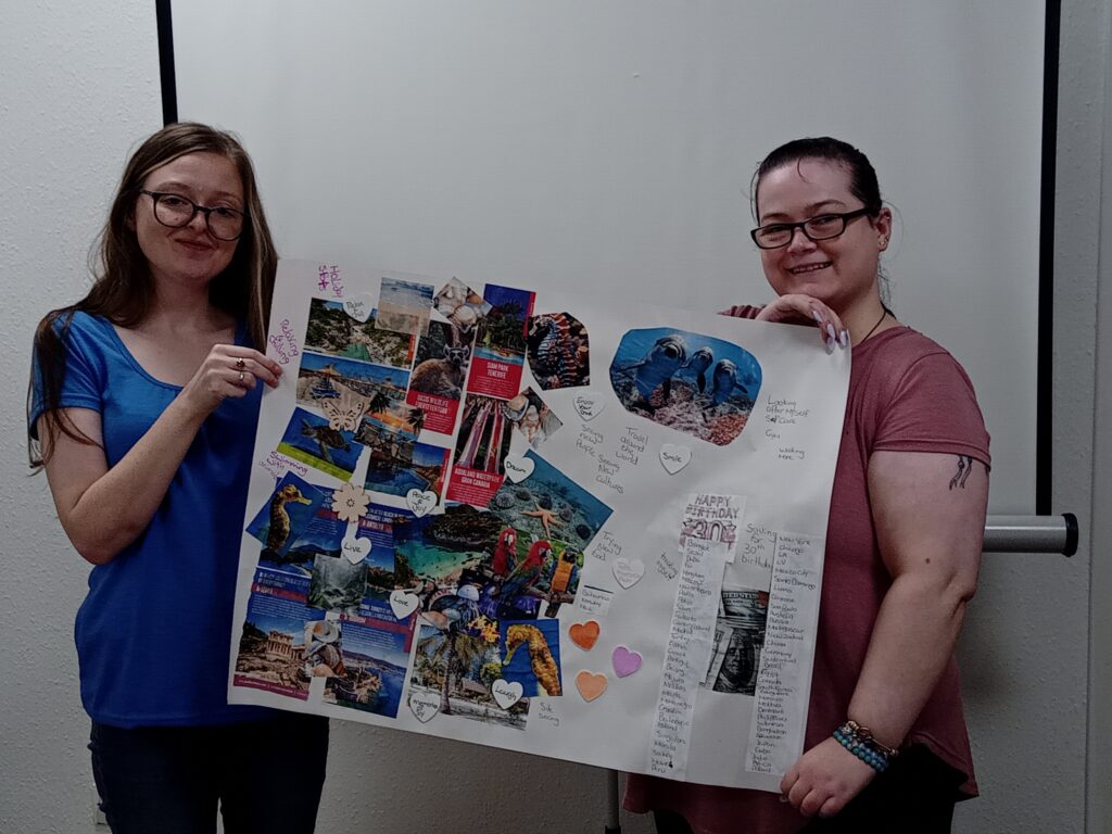 Nikita - Change Mental Health from left: Terry, Hearing Voices Outreach Worker and Nikita who reclaimed her voices through trauma-informed mental health support. Both holding a dream board Nikita made herself with all the locations she would love to visit
