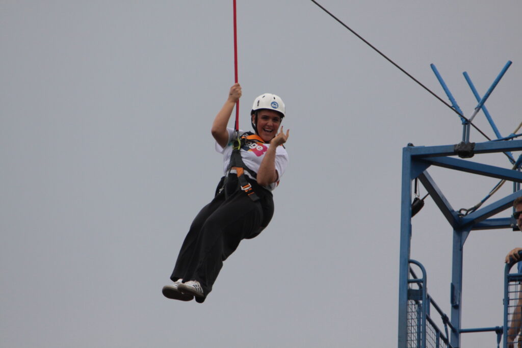 Young women hanging from zipline held by a harness