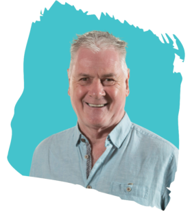 Smiling middle-aged man with gray hair wearing a light blue shirt, posed in front of a teal abstract background shape