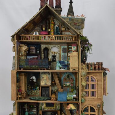 Detailed miniature dollhouse with multiple rooms, furniture, and decorations visible inside.