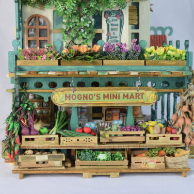 Miniature wooden market stall filled with colorful flowers and produce, labeled Mogno's Mini Mart.