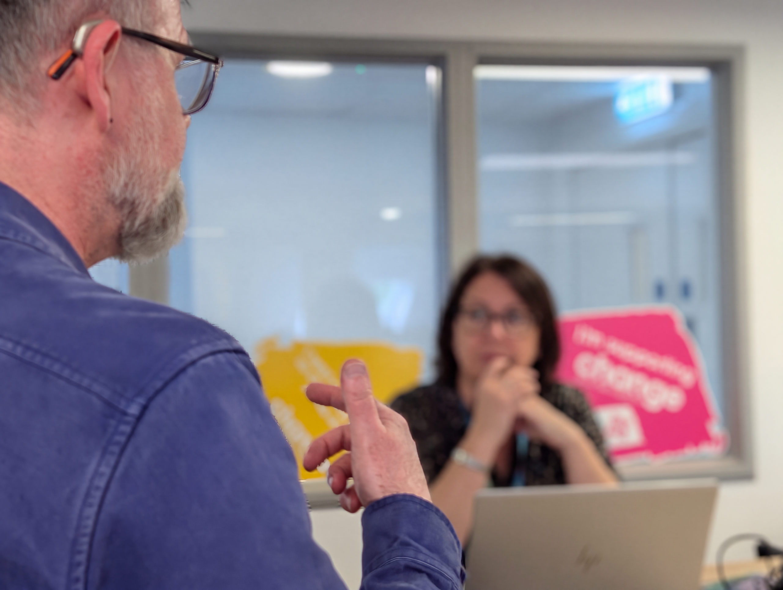 Neil - National Advice and Support Service Officer explaining something to a person in front. People talking about money worries and the steps they could take to change their finances